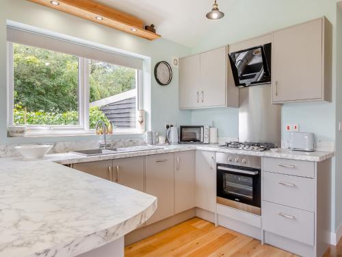a kitchen with white cabinets and a large window at Chestnut Lodge in Old Buckenham