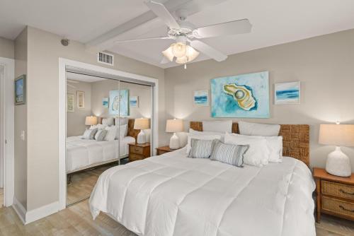 a bedroom with a large white bed and a ceiling fan at Beach Club, Unit 134 in East End