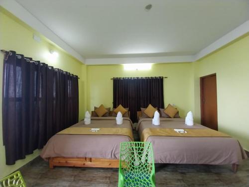 two beds in a room with yellow walls at Rupsadeya Homestay in Mangpu