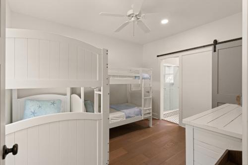 a white room with bunk beds and a ceiling fan at Getaway Cottage - 615 Bartow St in Saint Simons Island