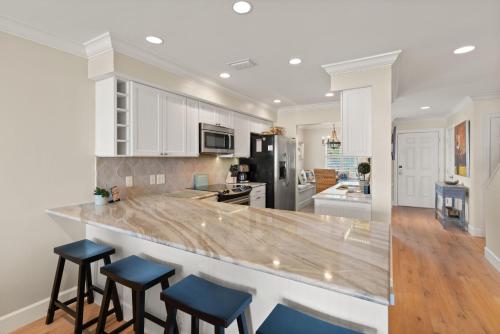 a kitchen with white cabinets and blue bar stools at Ocean Front Escape - 1106 Beachview Dr in Demere Park