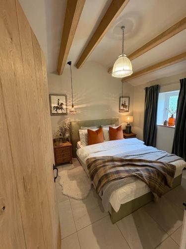 a bedroom with a bed with blue sheets and orange pillows at Holly Cottage - Village location, Lake District in Penrith