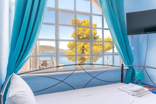 Schlafzimmer mit einem großen Fenster und einem Bett in der Unterkunft Wavedance Accommodation in Salamís