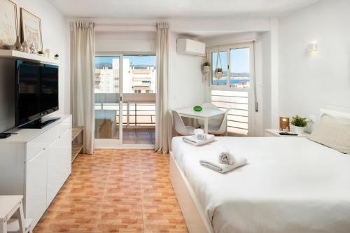 a white bedroom with a large bed and a television at Plazamar 039 in Torre del Mar