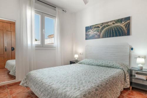 a white bedroom with a bed and two windows at Casandra in Tarifa