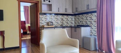 a kitchen with a white chair and a refrigerator at Moonlight Addis Hotel in Addis Ababa