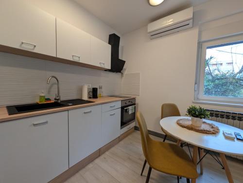 a kitchen with white cabinets and a table with chairs at Fully Equipped Studio in Sesvete in Sesvete