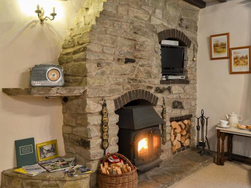 a stone fireplace with a television on top of it at Lower Barn in Wistanstow