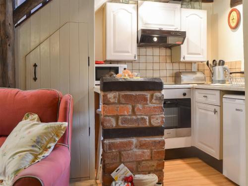 a kitchen with a brick oven in the middle of a room at Lower Barn in Wistanstow