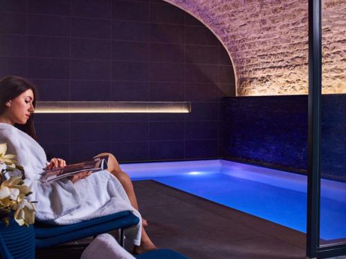 une femme assise sur une chaise dans une baignoire dans l'établissement Grand Hôtel La Cloche Dijon - MGallery Collection, à Dijon