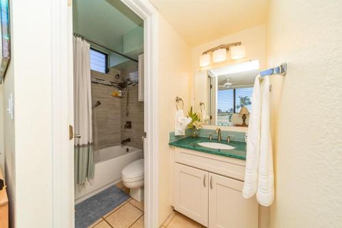 a bathroom with a sink and a toilet and a mirror at Kihei Akahi D402 · AKH D402 2BD Condo Across Beach Ocean View AC in Wailea