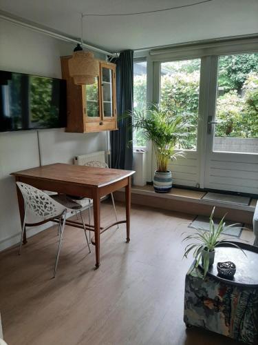 a dining room with a table and chairs and windows at Gezellig souterrain in bollestreek met prive ingang in Hillegom