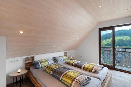 Dos camas en una habitación con una gran ventana. en Ferienwohnung Höfleblick, en Oppenau