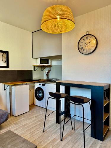 une cuisine avec une table, des chaises et une horloge dans l'établissement Studio 2 calme Av Georges Dumas - DABNB, à Limoges