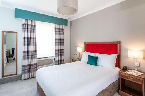 a bedroom with a large bed with a red headboard at The Craiglands Hotel Sure Hotel Collection by Best Western in Ilkley