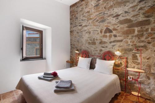 una camera da letto con un letto grande con un muro di pietra di Recanto d'Aldeia ad Alcoutim