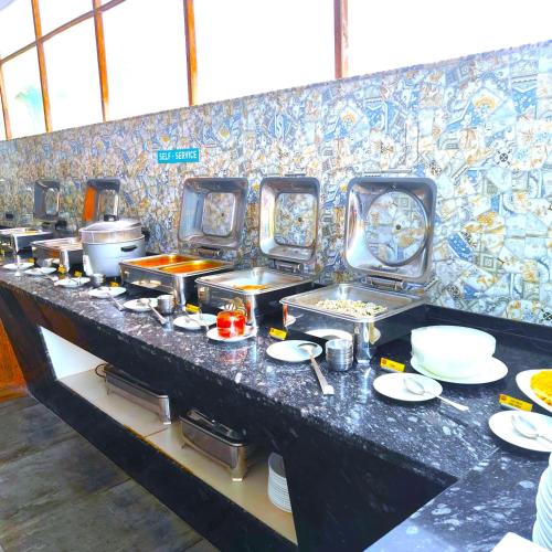 a buffet line with plates and utensils at Resort Terra Paraiso Goa - A Beach Property in Calangute