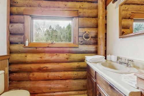 a bathroom with wooden walls and a sink and a window at Parker Lane Cabin in Weston