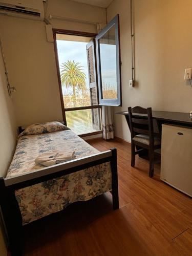 a bedroom with a bed and a chair and a window at Plaza Hotel Fray Bentos in Fray Bentos