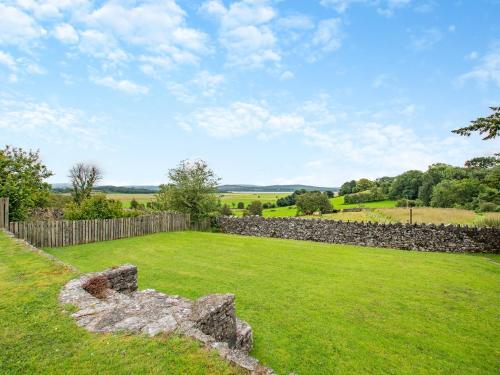 a garden with a stone fence and green grass at Arnside Apartment in Lindale