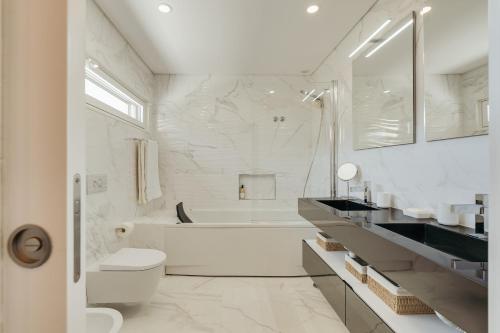 ein weißes Badezimmer mit einer Badewanne, einem WC und einem Waschbecken in der Unterkunft Paraty Villa in Aroeira