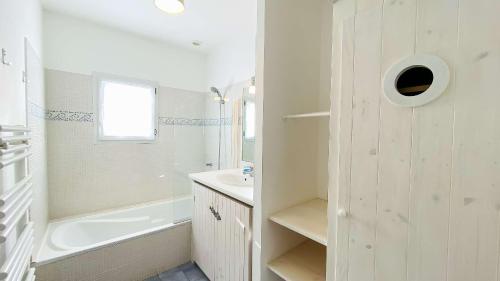 ein weißes Badezimmer mit Badewanne und Waschbecken in der Unterkunft Villa récente de style réthais avec piscine chauffée et jardin paysager in Le Bois-Plage-en-Ré