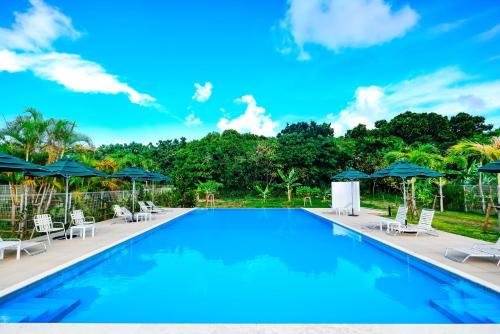 a large swimming pool with chairs and umbrellas at Seaside Village 13(シーサイドヴィレッジ・サーティーン) in Ishigaki Island