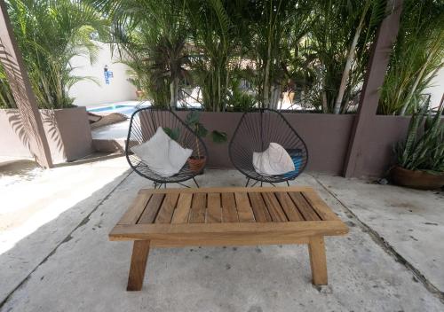 Dos sillas y una mesa de madera con un banco. en Casa Betina, en Puerto Escondido
