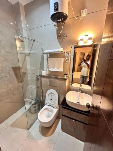 a person taking a picture of a bathroom with a toilet and sink at Joshi Homestay in Dehradun