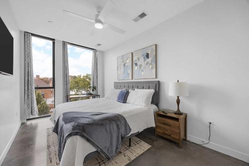 Habitación blanca con cama y ventanas grandes. en Chic Downtown Condo Steps from UIowa & Nightlife, en Iowa City