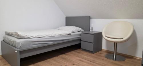 a small bed with a white chair and a desk at Wohnung für Monteure und beruflich Reisende in Petershagen