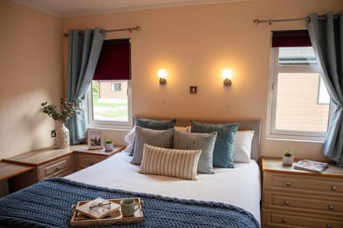 Un dormitorio con una gran cama blanca con almohadas azules. en Saffron Lodge With Hot Tub, en Malton