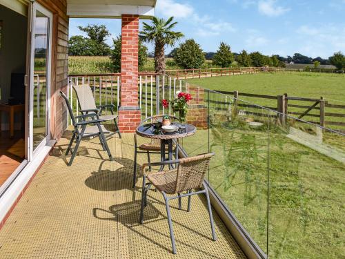 a patio with two chairs and a table and a fence at Cedar Lodge in Old Buckenham