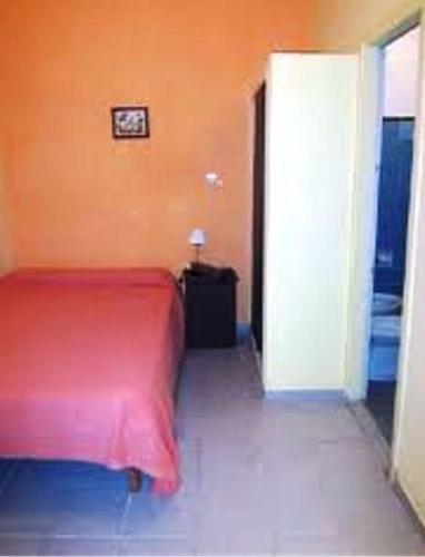 a red bed in a room with an orange wall at Mitre Suites in Buenos Aires