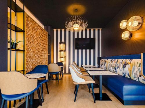 a dining room with a blue couch and tables and chairs at ibis Nancy Centre Stanislas in Nancy