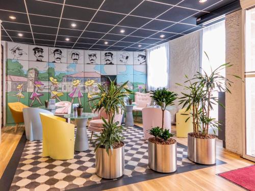 a restaurant with potted plants on a checkered floor at ibis Rochefort in Rochefort