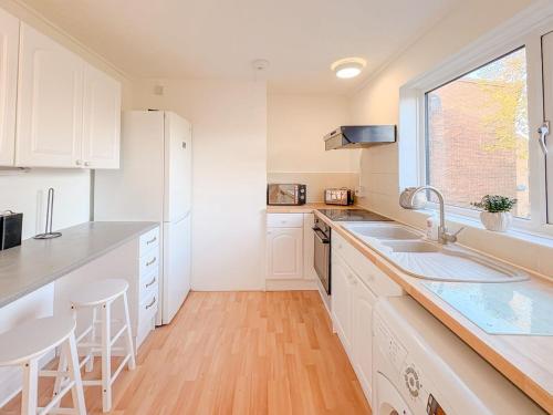 a kitchen with white cabinets and a sink and a window at Russet Grove in Earlham