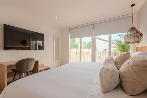 um quarto branco com uma cama grande e uma secretária em Casa Encanto - Corazón de Getsemaní em Cartagena de Indias