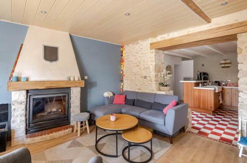 a living room with a couch and a fireplace at Longère de charme avec piscine, proche océan in Lairoux