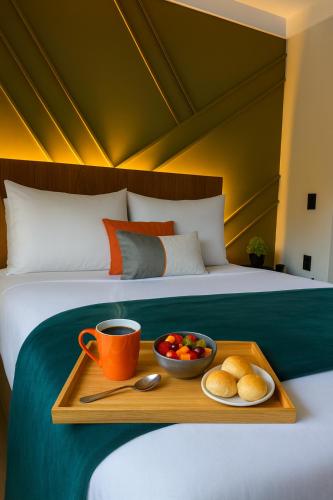 a tray with a cup of coffee and a bowl of fruit on a bed at Flat Praia Comfort Camburi in Vitória