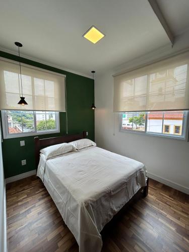 a bedroom with a bed with green walls and windows at Sobrado da Matriz in São Lourenço