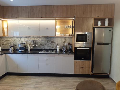 a kitchen with white cabinets and a stainless steel refrigerator at Luxurious Stella 2-bedroom Apartment with Pool in Hammamet Nord