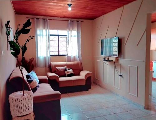 Una sala de estar con un sofá y un televisor. en Puxadinho do Sossego, en Presidente Epitácio