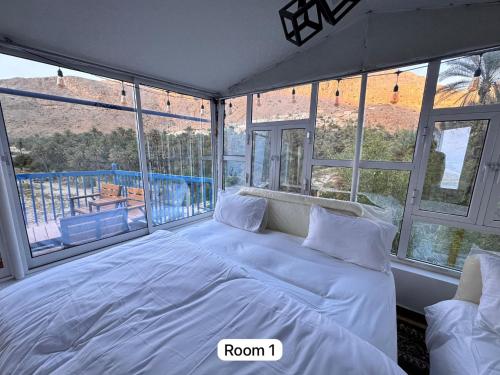 a bedroom with a large white bed in front of windows at Hawer Inn - wadi bani Khalid in Biḑ‘ah
