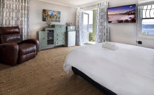 a bedroom with a large white bed and a chair at LIMA HOUSE, Seaforth, Simon's Town in Simonʼs Town
