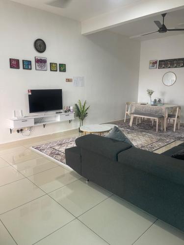 a living room with a black couch and a tv at Anis Homestay MELAKA in Melaka