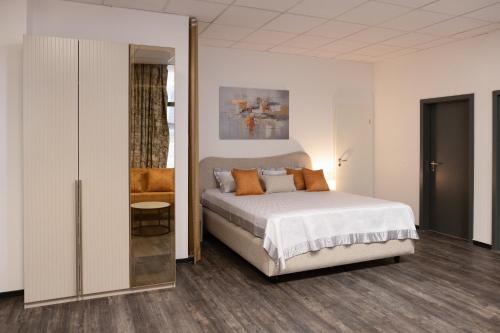 ein weißes Schlafzimmer mit einem Bett und einem Spiegel in der Unterkunft Arbio I Urban Apartment Zimmerstrasse in Leipzig