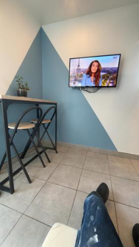 a person laying on the floor in a room with a tv on the wall at Petit studio à la campagne proche cnpe paluel in Angerville-la-Martel