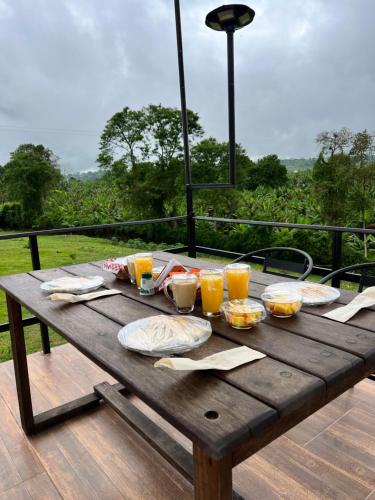 een houten tafel met eten en glazen sinaasappelsap bij Persea Hospedaje in Armenia