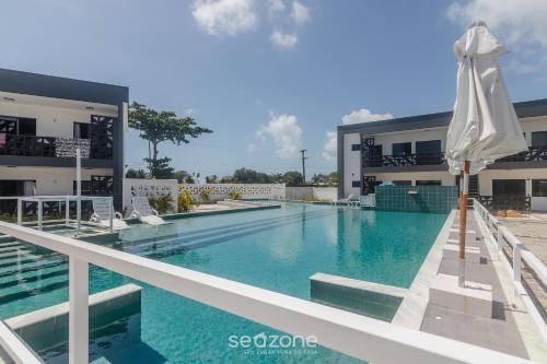 a swimming pool with an umbrella in front of a building at Aptos em condo. com churrasq. e piscina na melhor localização de Porto Seguro – DVBs in Porto Seguro